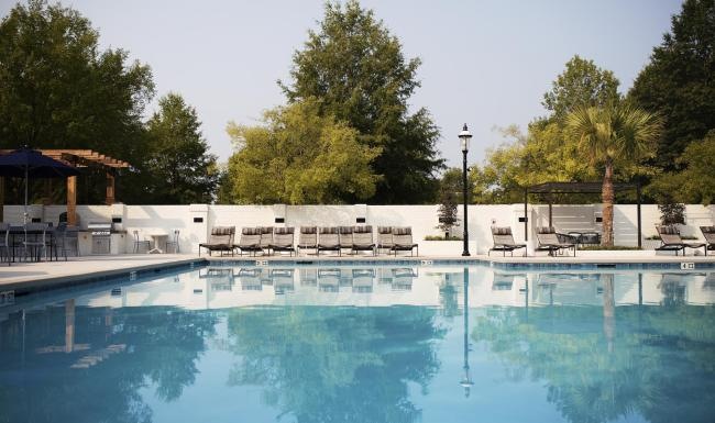 a swimming pool with chairs and umbrellas by it